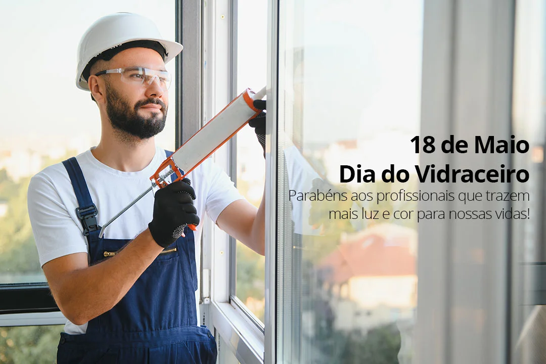 Fotografia de um vidraceiro profissional com capacete e macacão azul aplicando selante em uma janela de sacada envidraçada, com vista para a cidade. O topo da imagem contém o texto comemorativo: "18 de Maio | Dia do Vidraceiro. Parabéns aos profissionais que trazem mais luz e cor para nossas vidas!