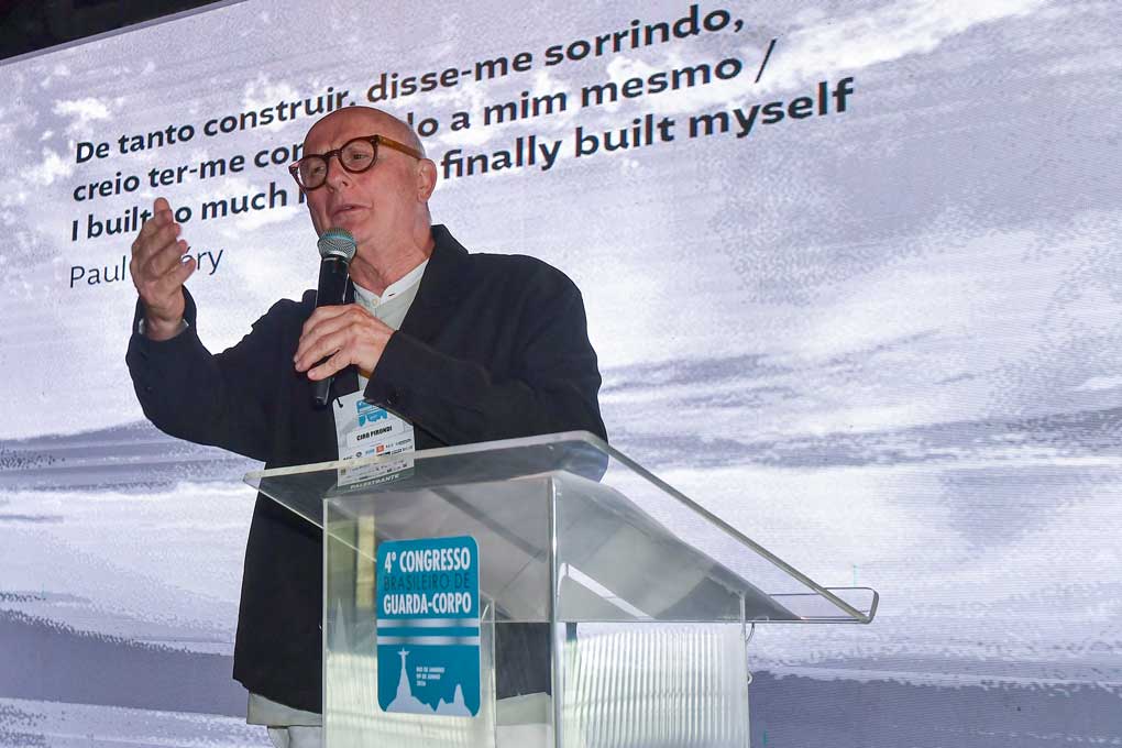 Arquiteto falando em microfone num púlpito num Congresso de Guarda Corpo painell de led ao fundo