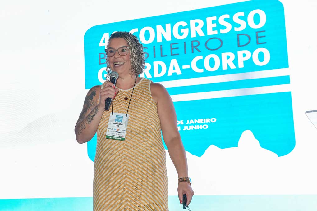 Engenheira Michele Gleice Silva diretora do ITEC falando ao microfone, painel do 4º Congresso Brasileiro de Guarda Corpo ao fundo
