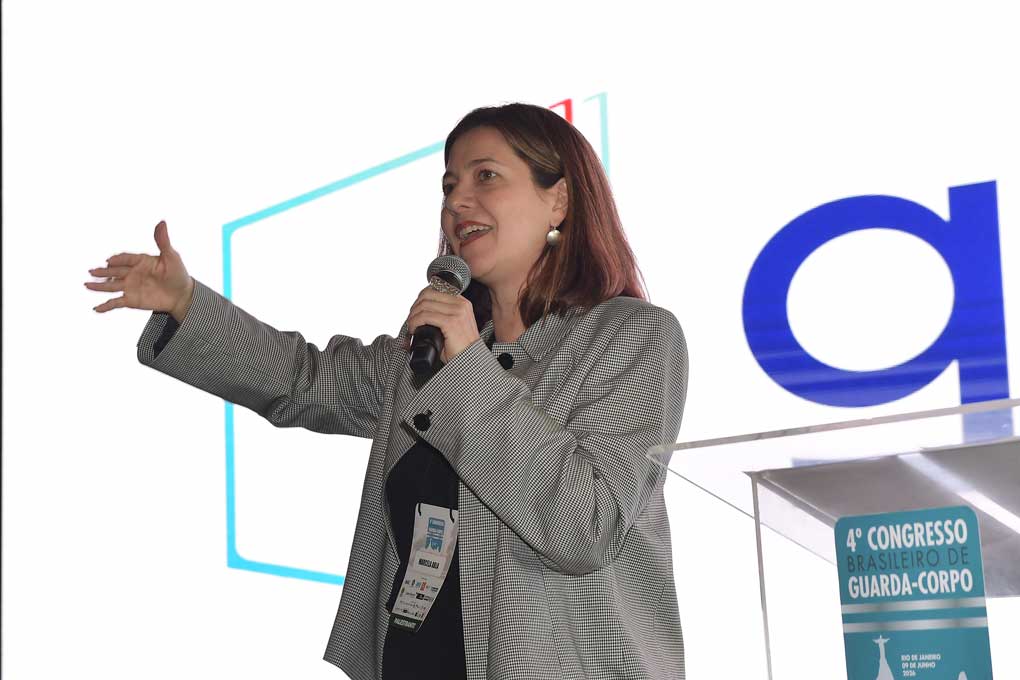 Arquiteta palestrante falando para platéia com um painel de led de fundo